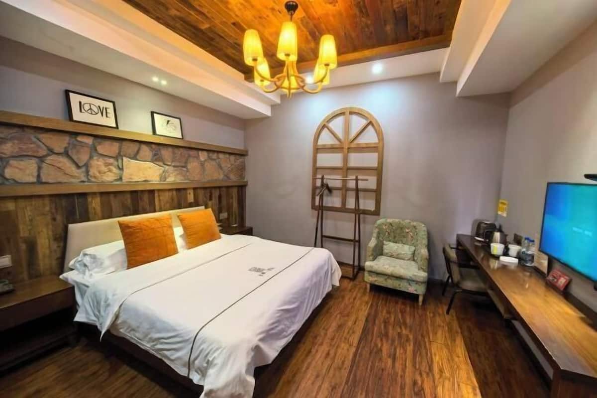 Une chambre à coucher avec un lit, une tête de lit en bois, un lustre, une télévision et un mur en pierre.