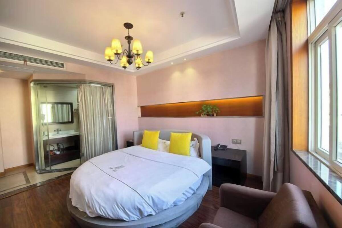 Une chambre d’hôtel avec un lit, un bureau, une chaise, un miroir et une fenêtre.