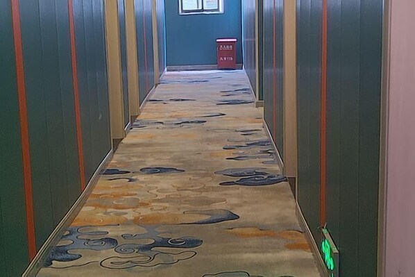 Un pasillo con alfombra estampada y paredes a rayas verticales.