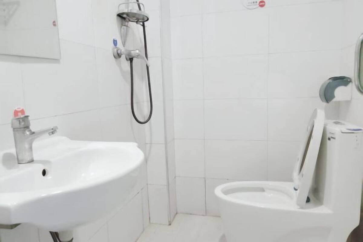 Une salle de bain avec un lavabo, des toilettes et une douche, le tout de couleur blanche.
