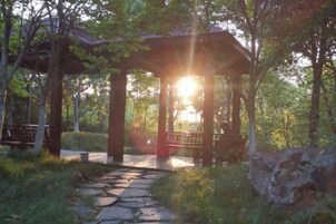 A gazebo with a stone pathway leading to it, surrounded by greenery.