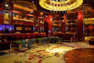 Un interior lujoso con muebles ornamentados, un candelabro y una alfombra con motivos florales.