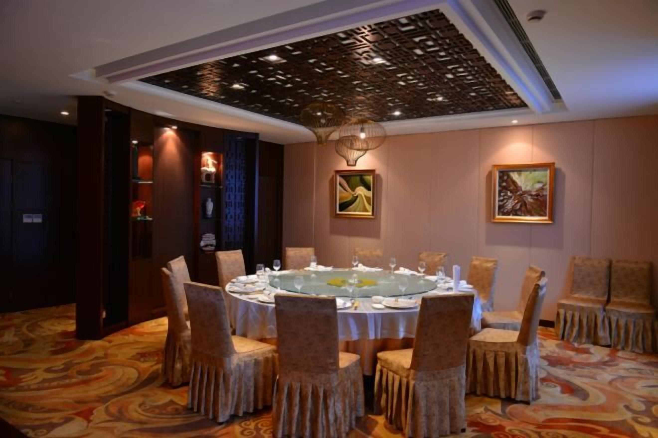 A round dining table with chairs, a patterned carpet, and artwork on the walls.