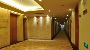 A hotel corridor with wooden doors, a patterned carpet, and a long hallway with overhead lighting.