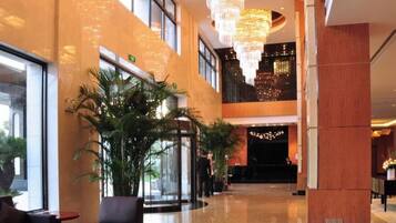 Hall d'albergo con reception, area salotto e un grande lampadario.