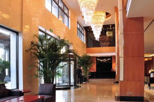Un vestíbulo de hotel con mostrador de recepción, zona de estar y una gran araña.