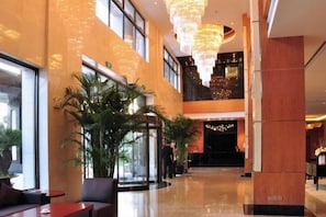 A hotel lobby with a reception desk, seating area, and a large chandelier. - Oriental Hotel (Taicang)