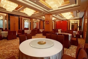 Comedor de hotel con mesas redondas, techos altos y candelabros.