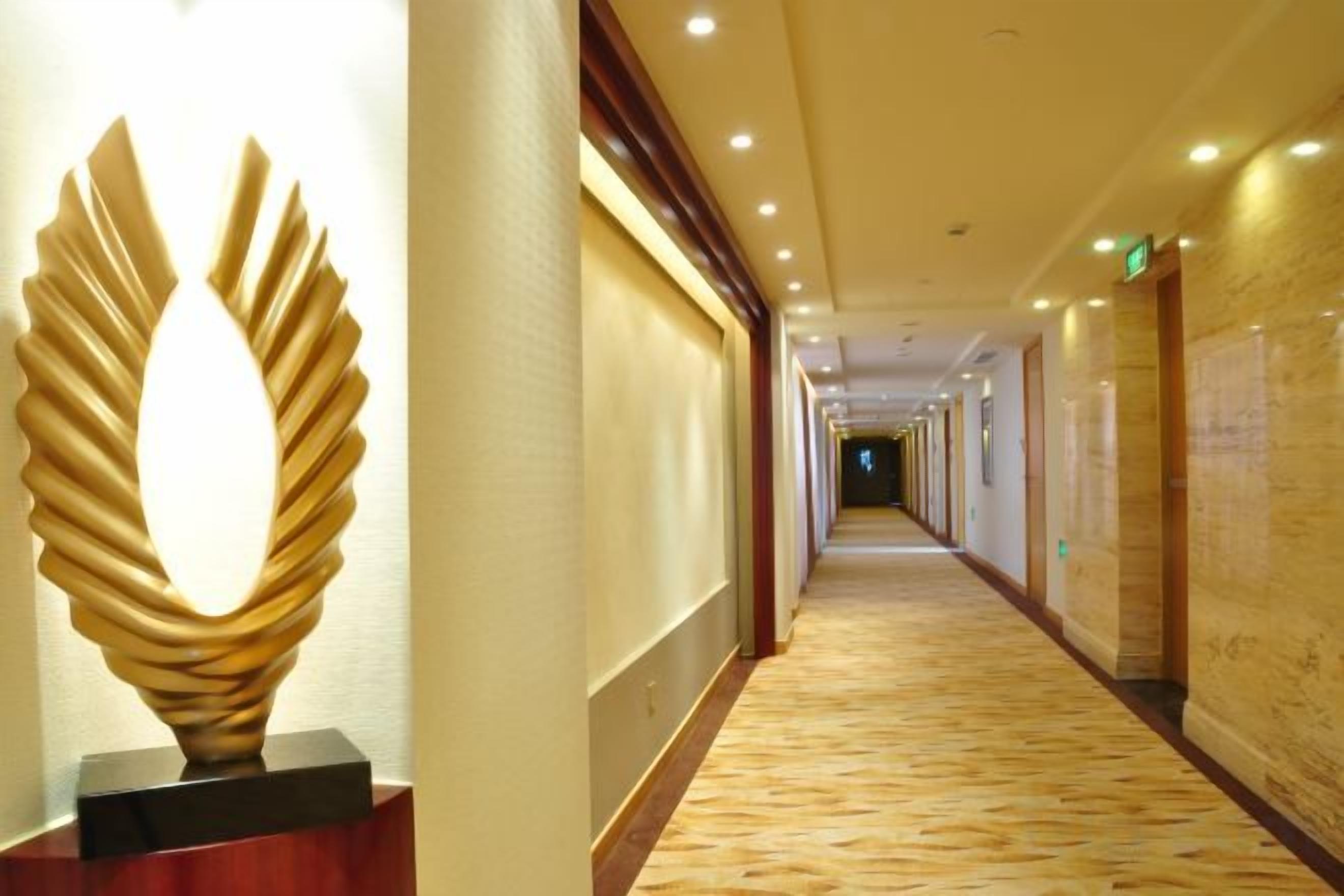 A hotel corridor with a modern sculpture, a carpeted floor, and a long hallway with doors on one side.