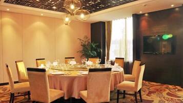 A dining area with a round table set for six, surrounded by chairs, in a room with patterned carpet and a decorative ceiling.