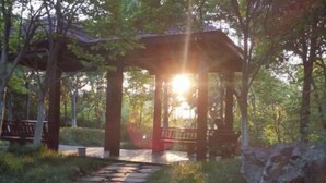 A gazebo with a stone pathway leading to it, surrounded by trees and greenery. - Oriental Hotel (Taicang)
