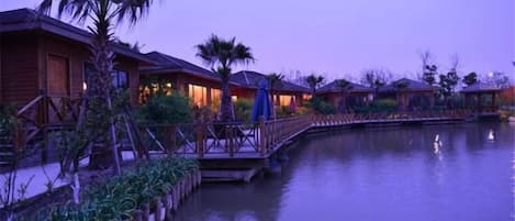 Un complejo turístico frente al mar con bungalows sobre el agua conectados por un puente de madera.