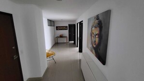 Ein Flur mit einem Buddha-Gemälde, einem kleinen Tisch mit einer Vase und einem Stuhl.