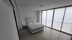 Ein modernes Schlafzimmer mit einem großen Bett, einem Nachttisch und einem Fenster mit Jalousien.