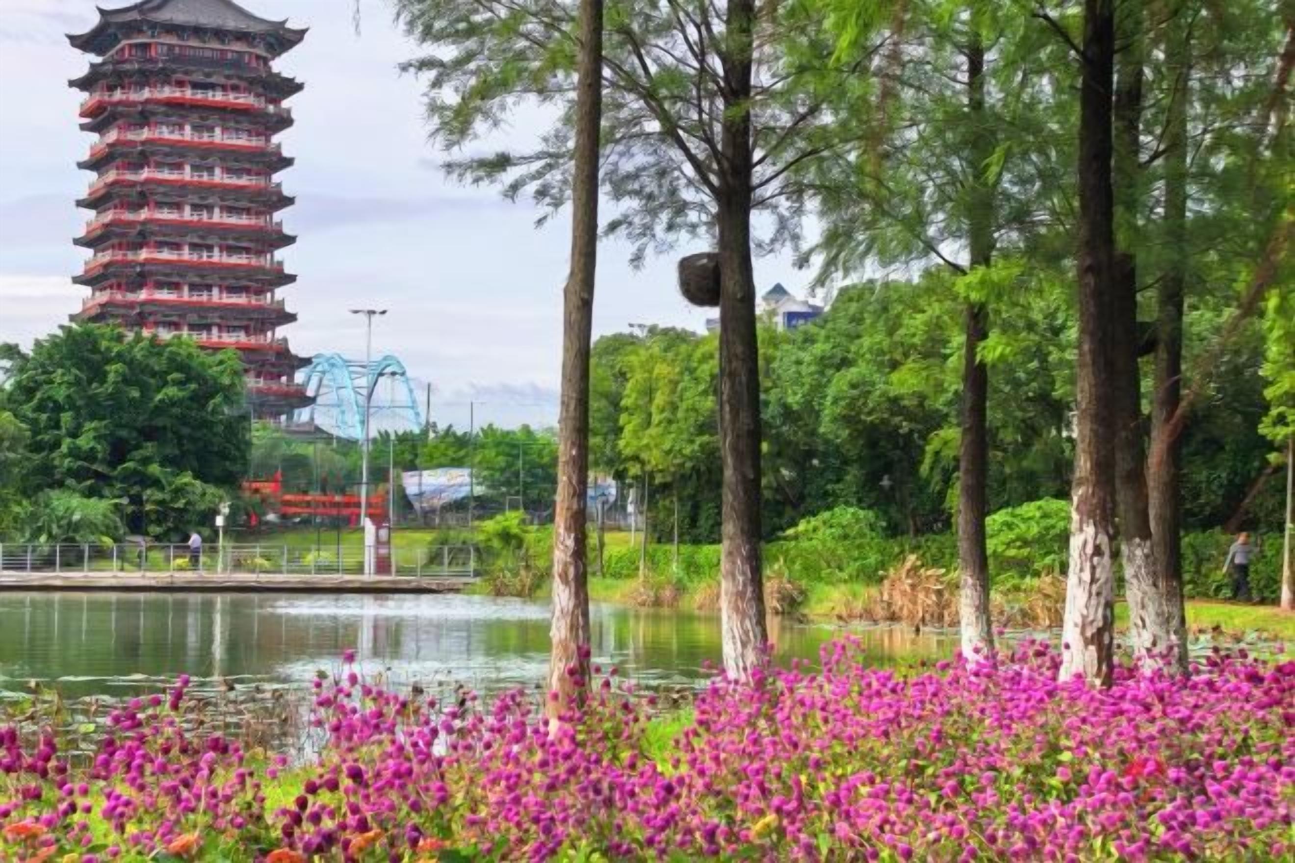 Una torre de estilo pagoda, una masa de agua y un campo de flores rosadas.