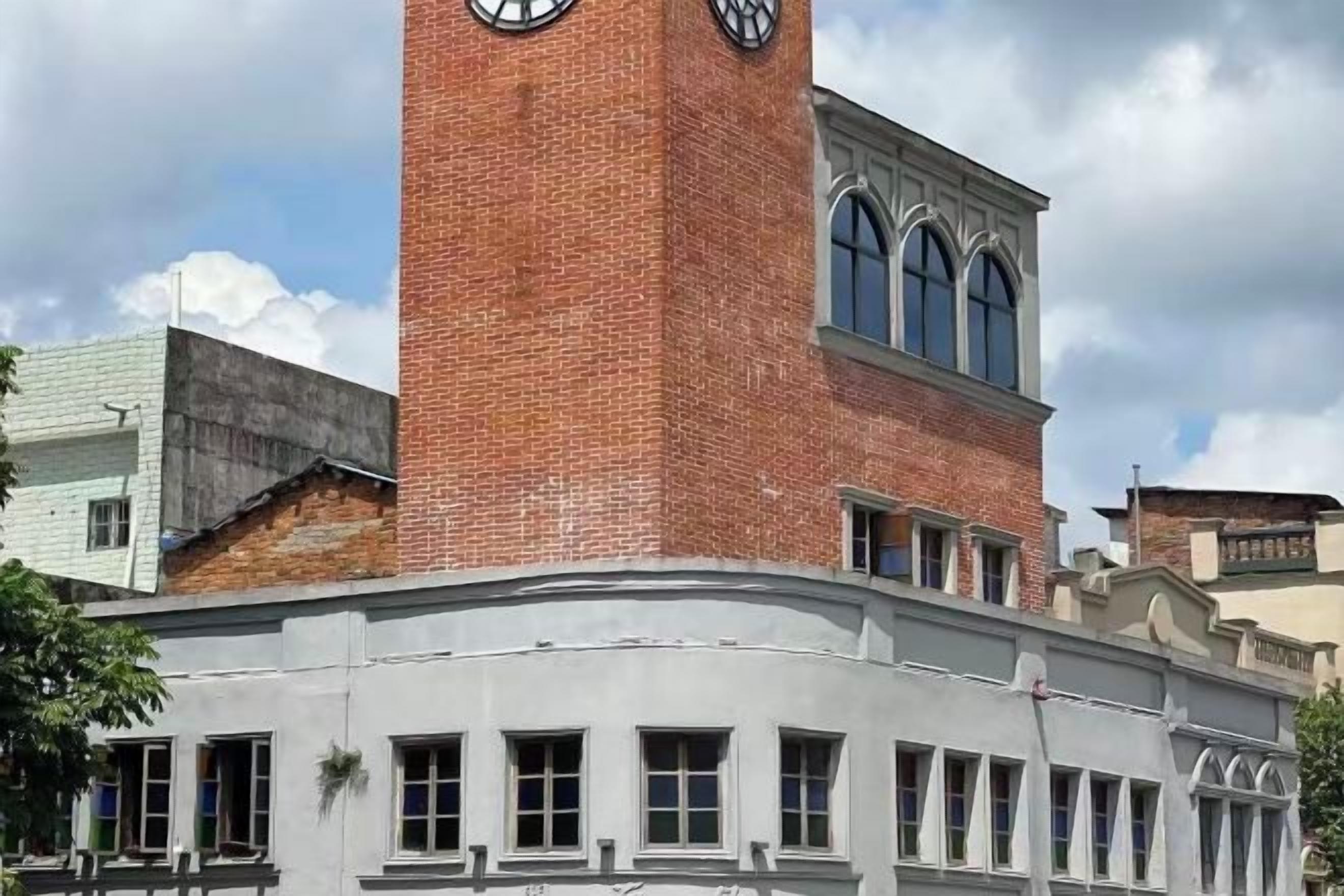 A brick tower with a clock, a curved facade, and arched windows.