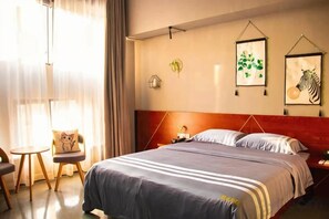 Ein Hotelzimmer mit Bett, Nachttisch, Stuhl und einem Kunstwerk an der Wand.