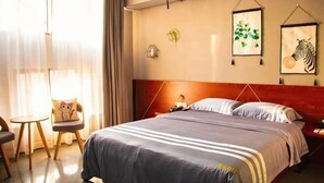 A hotel room with a bed, bedside table, chair, and artwork on the wall. - Huaijia Art Hotel (Qinzhou)