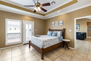 Ein Schlafzimmer mit einem Bett, einem Deckenventilator, einem kleinen runden Tisch und Blick ins Freie.