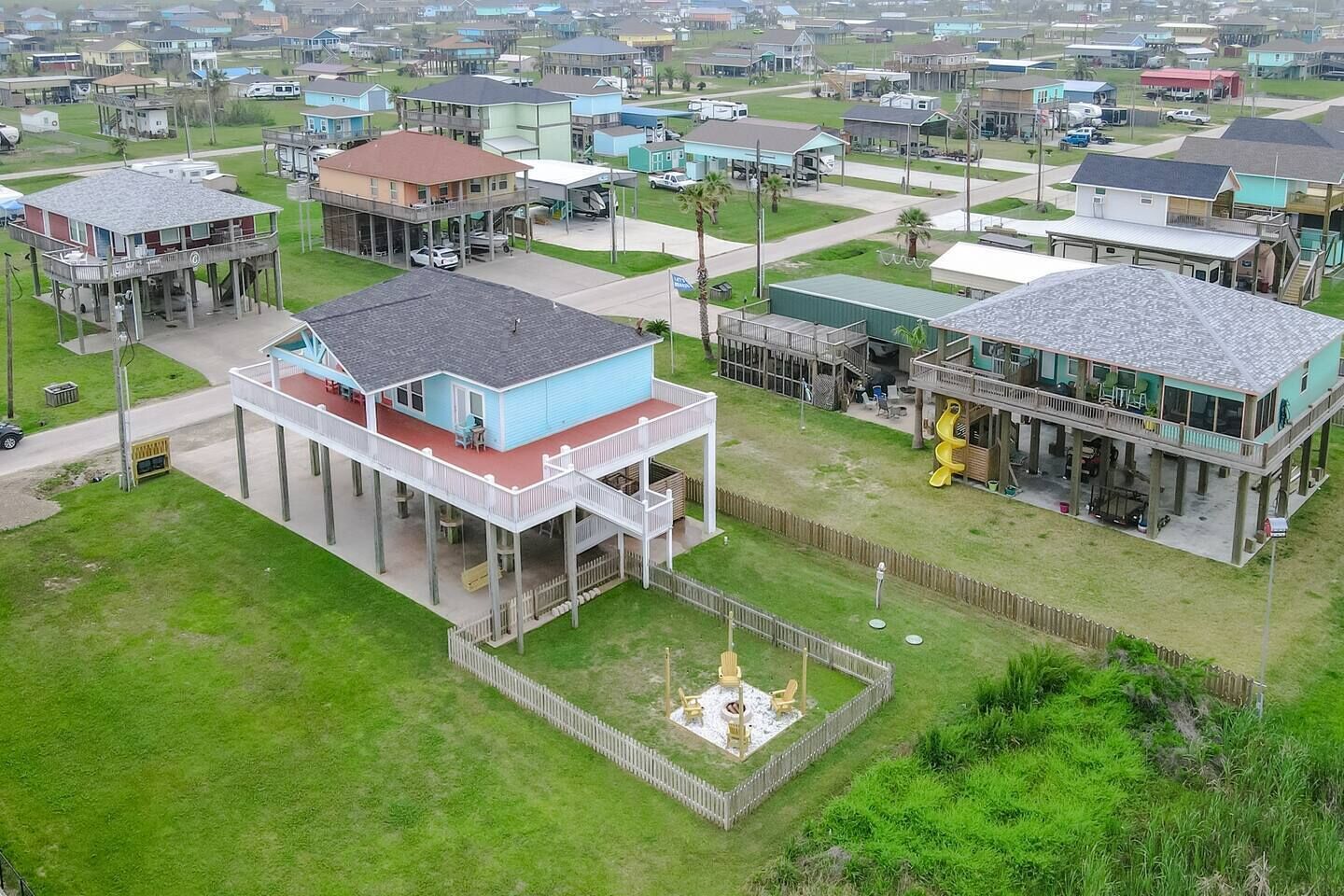 A residential area with houses featuring elevated structures and a central courtyard with a fire pit.