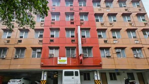 Un edificio de varios pisos con fachada roja y beige, múltiples balcones y un letrero que indica que es una posada urbana.
