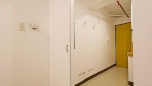 Un pasillo con una puerta, un interruptor de luz y un teléfono en la pared.