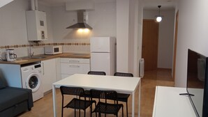 A compact kitchen with a washing machine, microwave, and a dining area with a table and chairs.