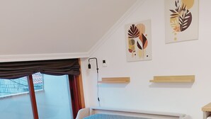 A modern bedroom with a bed, a desk, and a window.