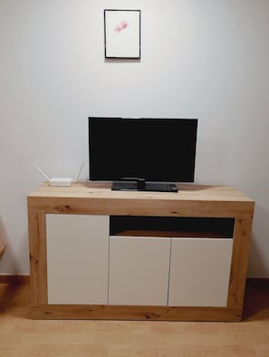 Un meuble en bois pour la télévision, avec un téléviseur à écran plat, une télécommande et un projecteur.