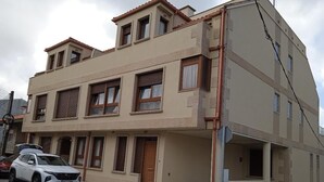A multi-story residential building with a flat facade, several windows, and a visible garage door.