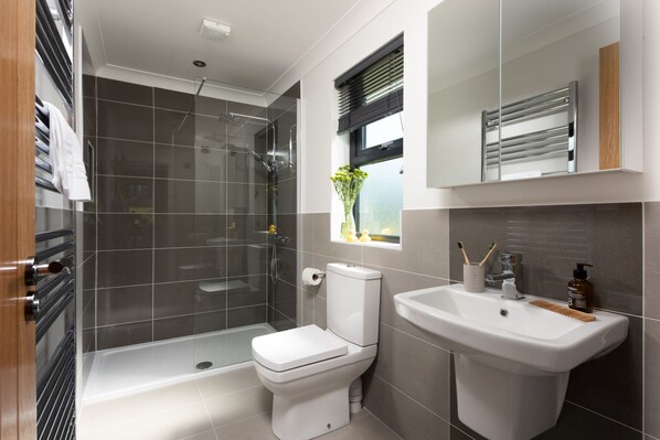 Een moderne badkamer met een douchecabine van glas, een toilet en een wastafel.