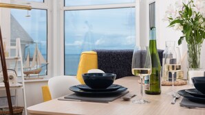 A dining table with black bowls, wine glasses, and a bottle, set against a window with a view of a building.