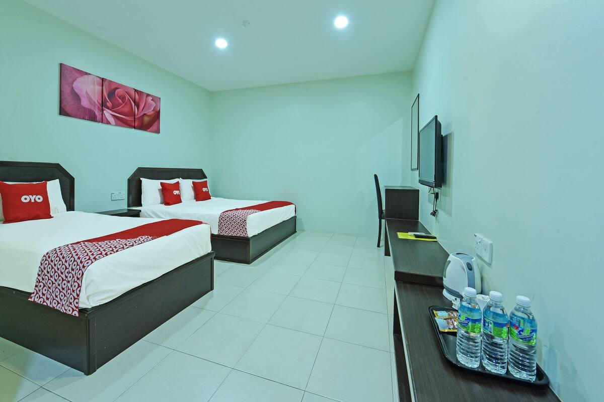 Una habitación de hotel con dos camas, televisión, escritorio y dispensador de agua.