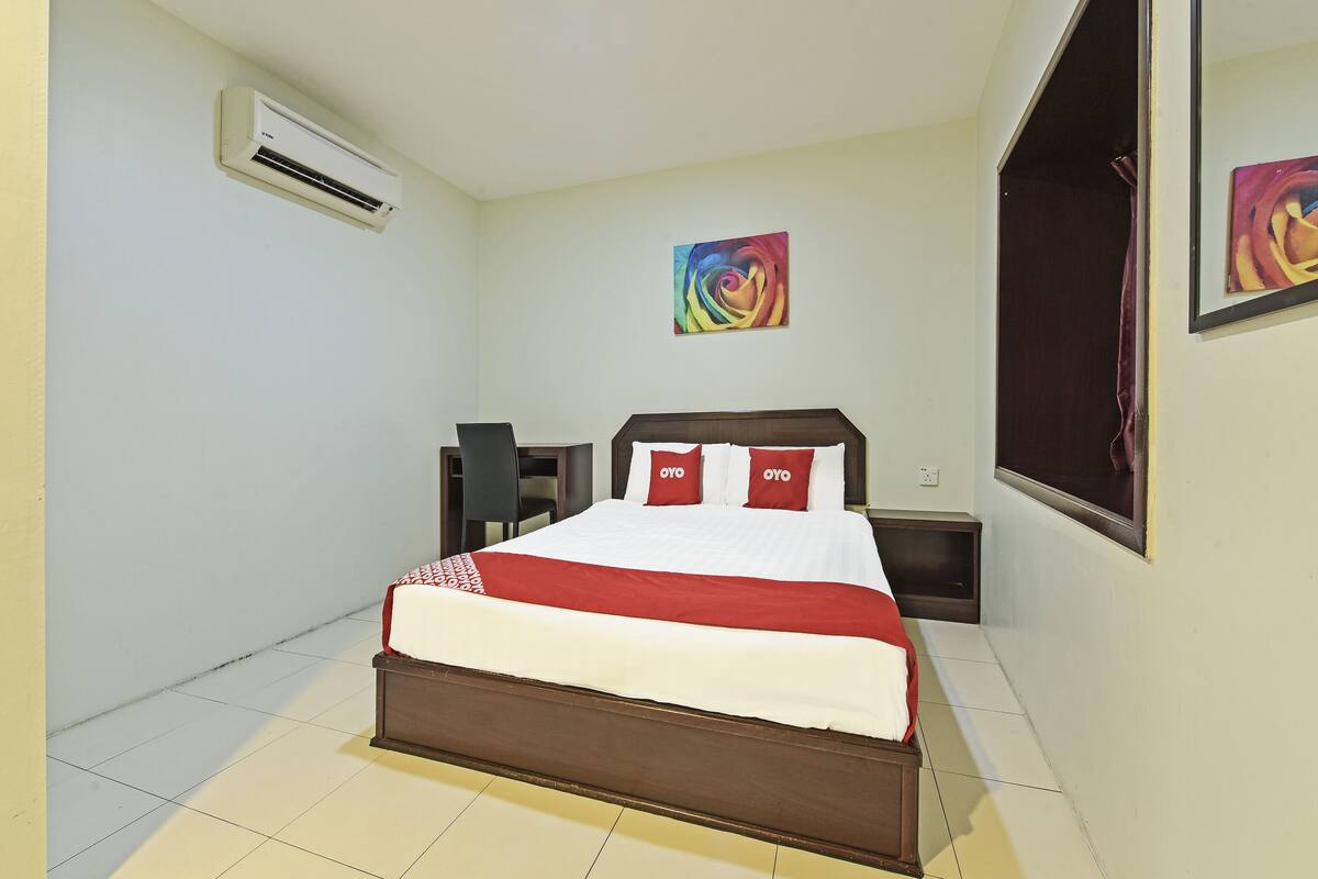 Un dormitorio con cama, escritorio, aire acondicionado y ventana.