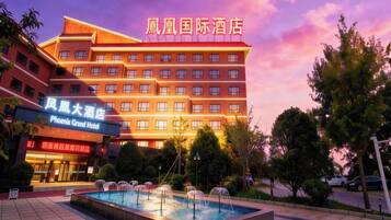 Un hôtel à plusieurs étages, doté d’une piscine et d’une enseigne indiquant « Phoenix Grand Hotel ».