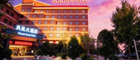A hotel with multiple floors, a swimming pool, and a sign for Phoenix Grand Hotel.