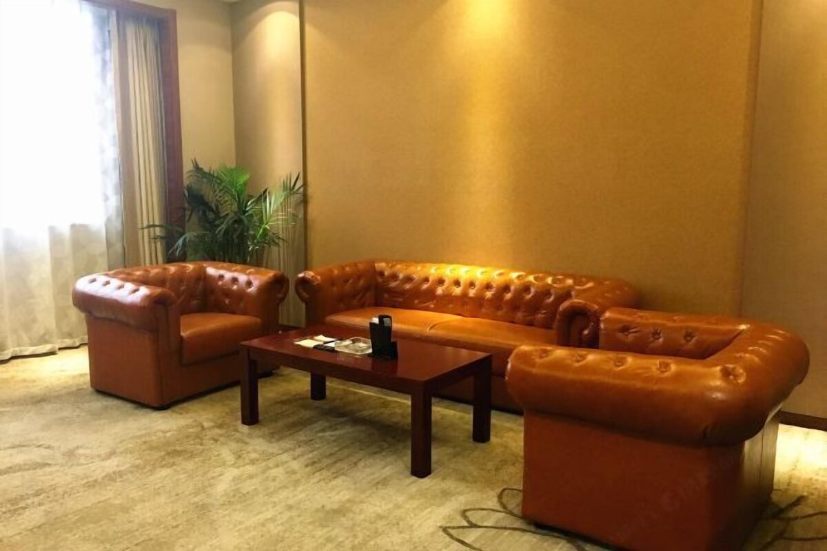 A room with a brown leather sofa, a matching armchair, and a wooden coffee table.