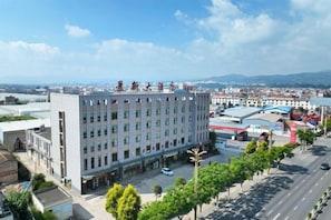 A multi-story hotel with a central courtyard, surrounded by trees and a parking lot. - Jingxin Hotel (Yuxi)