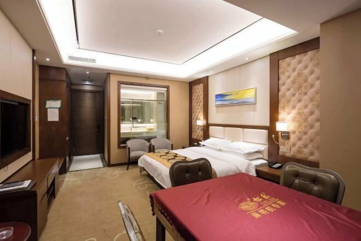 A hotel room with a bed, a desk, a TV, and a dining table.