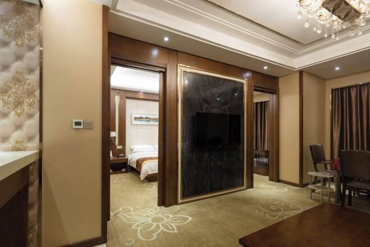 A hotel room with a bed, a TV, a desk, and a dining area.