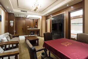 A hotel room with a dining table, a sofa, a small table, and a TV.