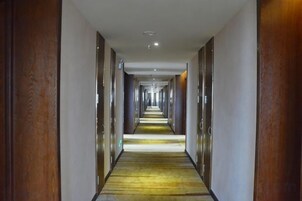 Un largo y estrecho pasillo de hotel con puertas a ambos lados, que conduce a habitaciones individuales.
