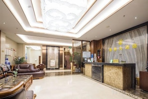 A hotel lobby with a reception desk, seating area, and a large chandelier. - Jingxin Hotel (Yuxi)