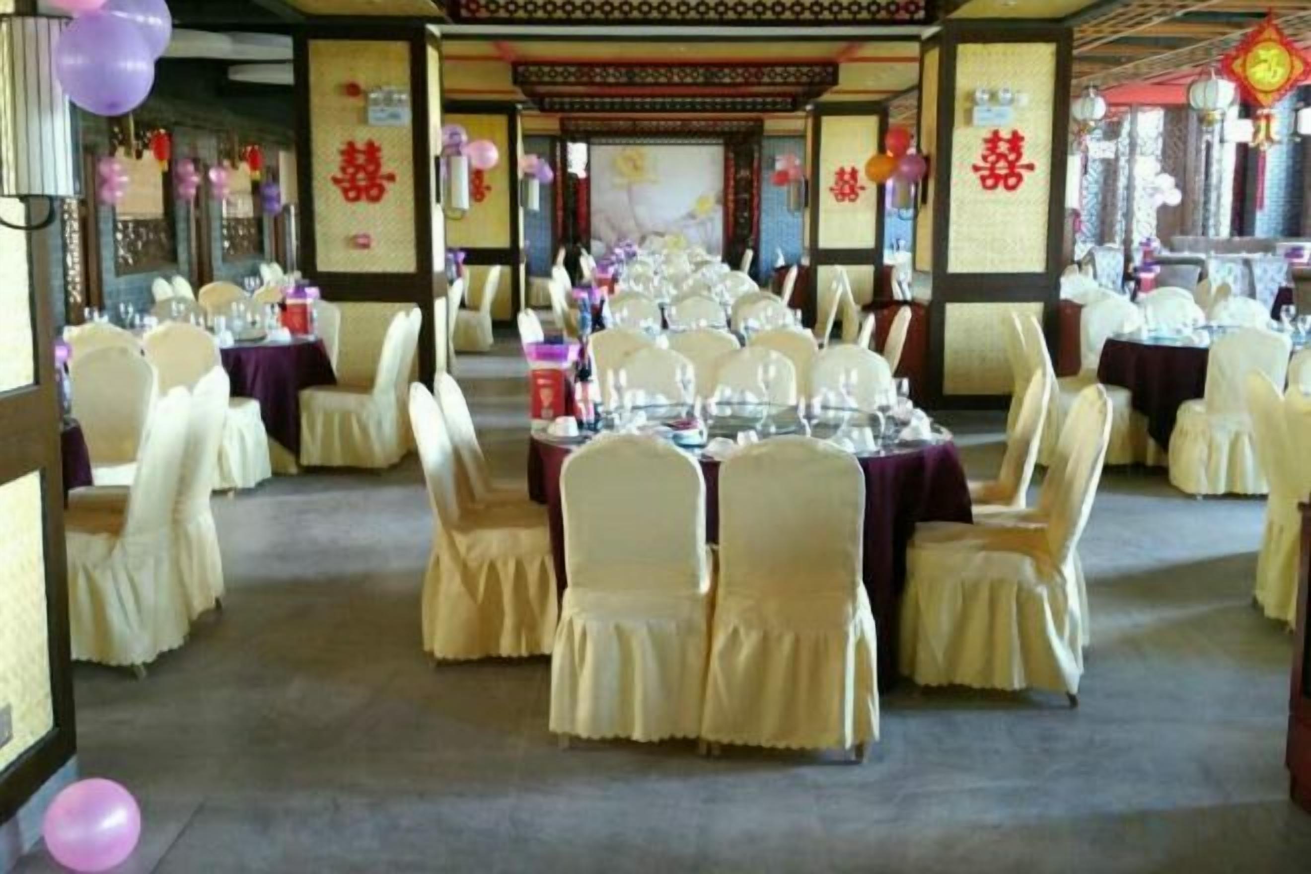 Un salón de banquetes con mesas redondas, sillas y una entrada de estilo asiático tradicional.