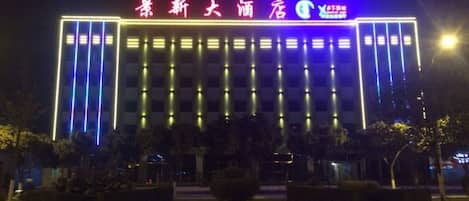 A hotel with a modern facade, illuminated signage, and a structured entrance.