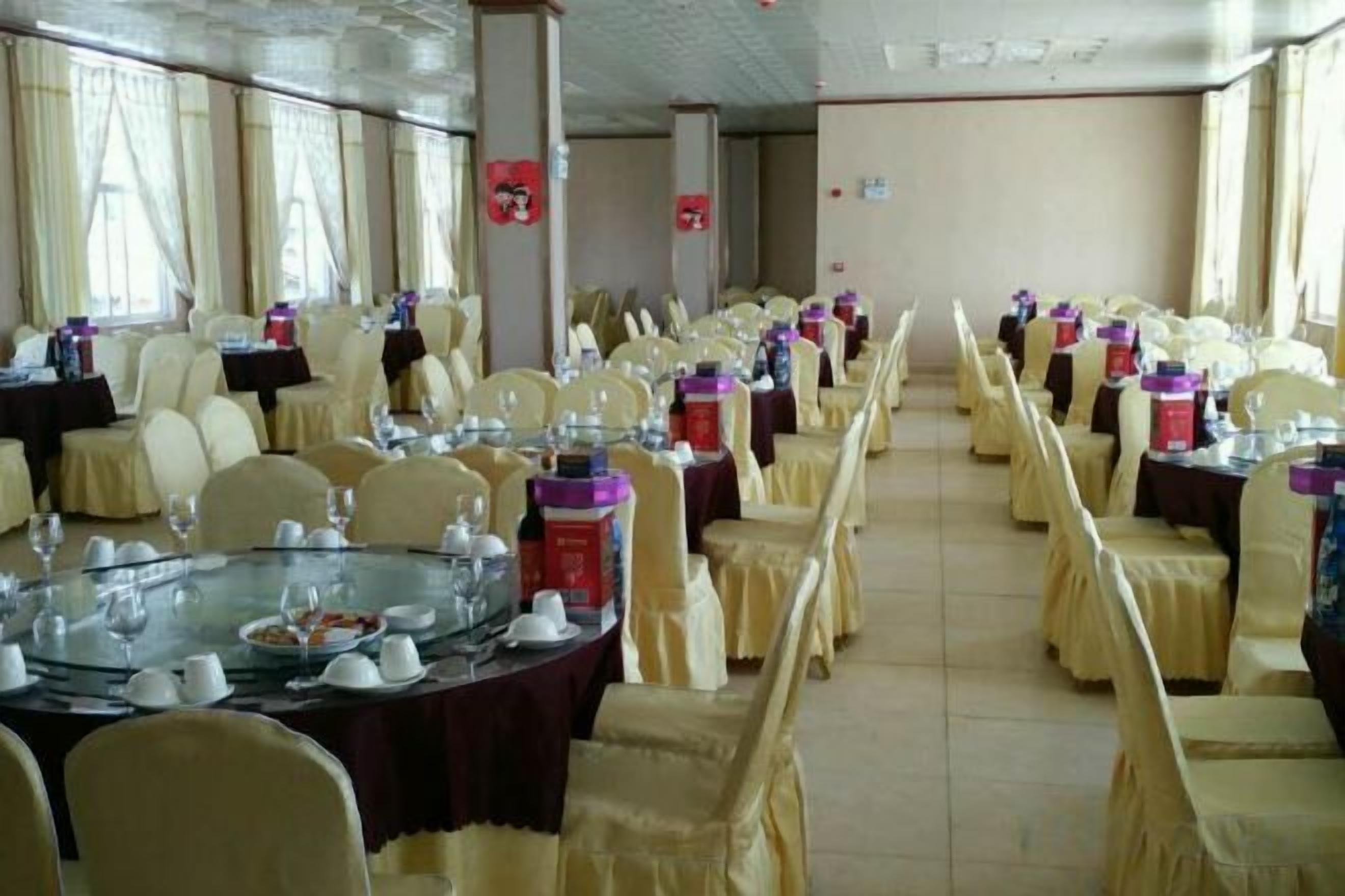 Un salón de banquetes con mesas redondas, sillas y una mesa larga con un centro de mesa de cristal.