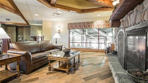 A cozy living room with a leather sofa, a coffee table, and a stone fireplace.