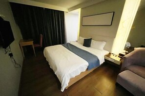 A hotel room with a large bed, a bedside table, a chair, a TV, and a curtain. - Ke'erma Business Hotel (Zhongshan)