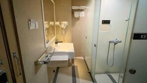 Ein Hotelbad mit Waschbecken, Spiegel, Handtuchhalter und Dusche.