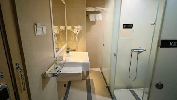 Un bagno d'albergo con lavandino, specchio, portasciuga e doccia.